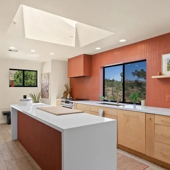 The finished kitchen with a skylight and a red tile wall
